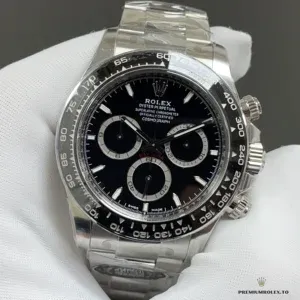 Steel Daytona 126500LN with black dial and black bezel held in a white glove against a grey background