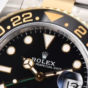 Close-up of a GMT-Master II 116713LN black ceramic bezel insert with gold-toned numerals and black dial