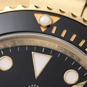 Macro of the lume pip at 12 on a Submariner 126618LN black bezel insert with gold-toned markers