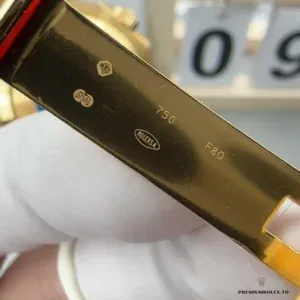 Close-up of black dial with gold-rimmed hour markers and Mercedes hands