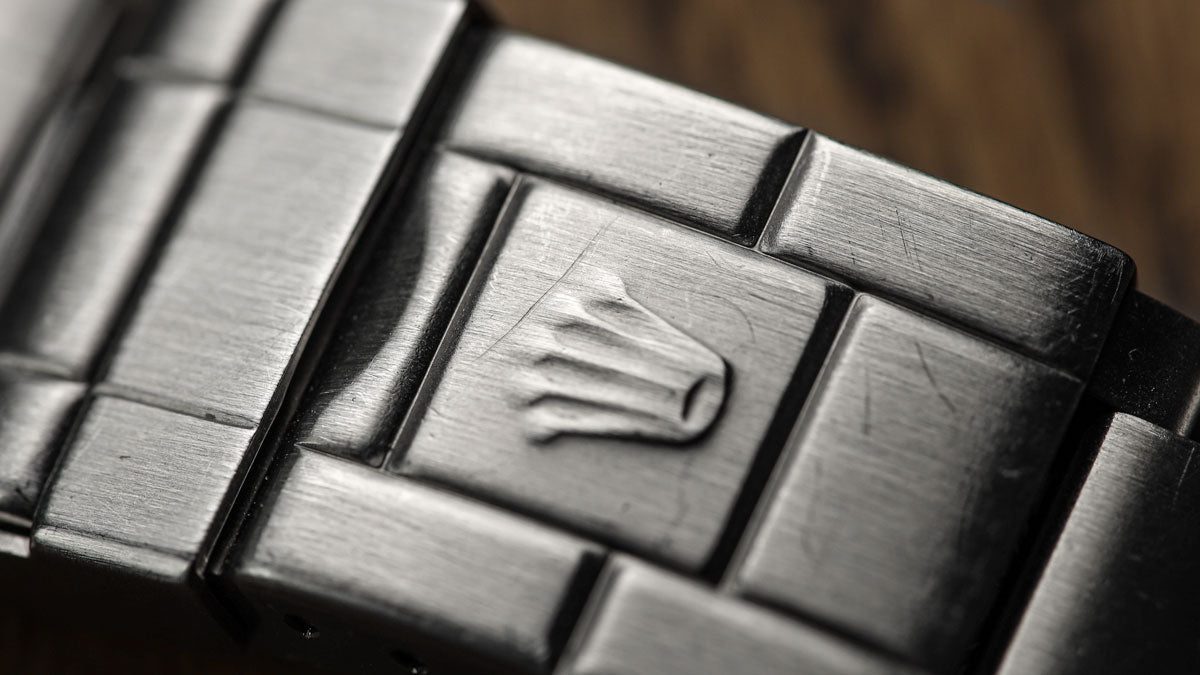Watch bracelet clasp macro showing everyday scratches on brushed stainless steel surface