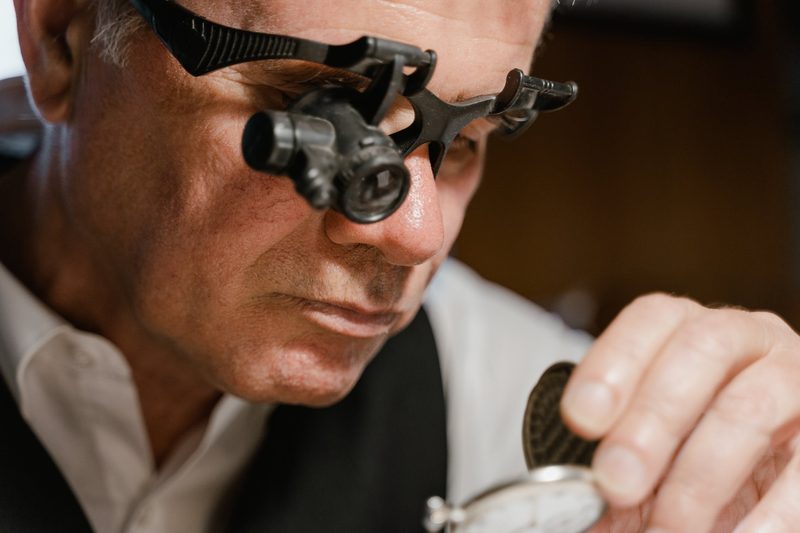 Professional jeweler inspecting a watch through a loupe
