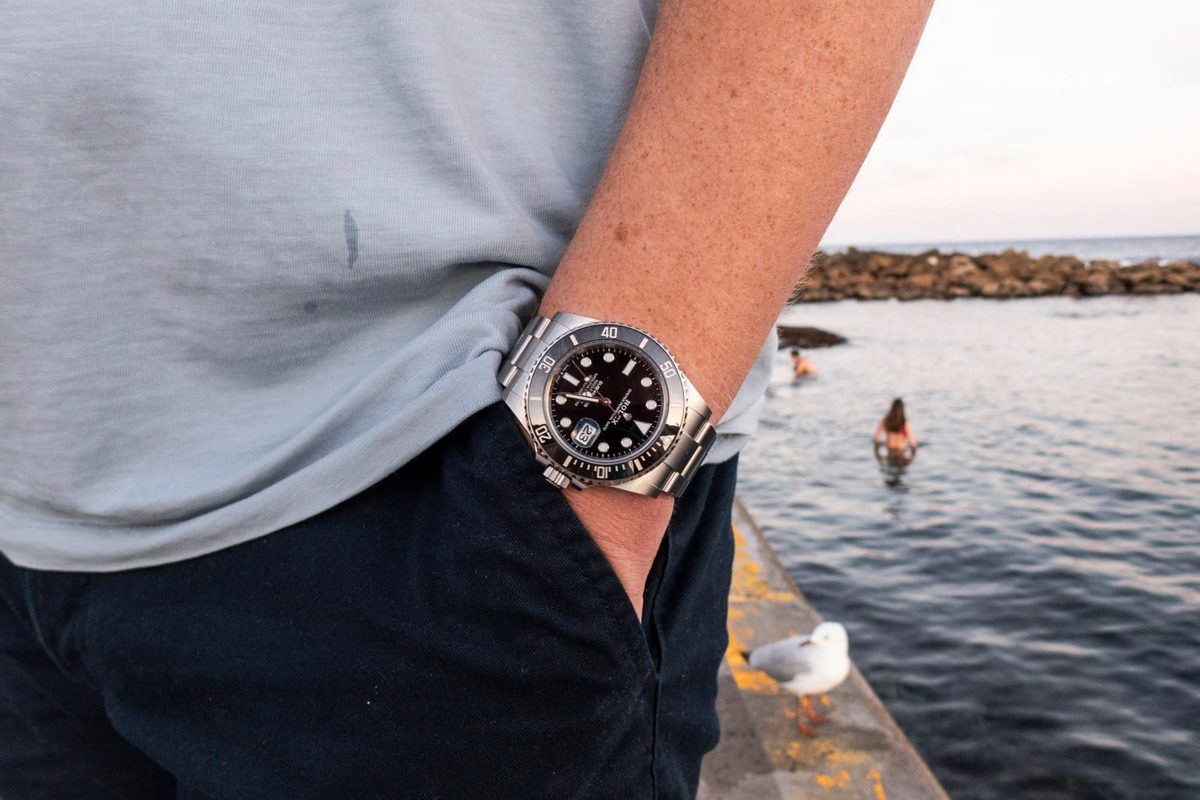 Rolex Submariner on wrist at seaside showing dive watch in natural outdoor setting