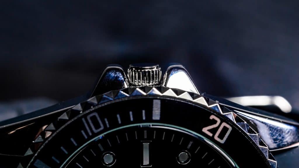 Watch screw-down crown close-up between crown guards showing sealed position on dive watch